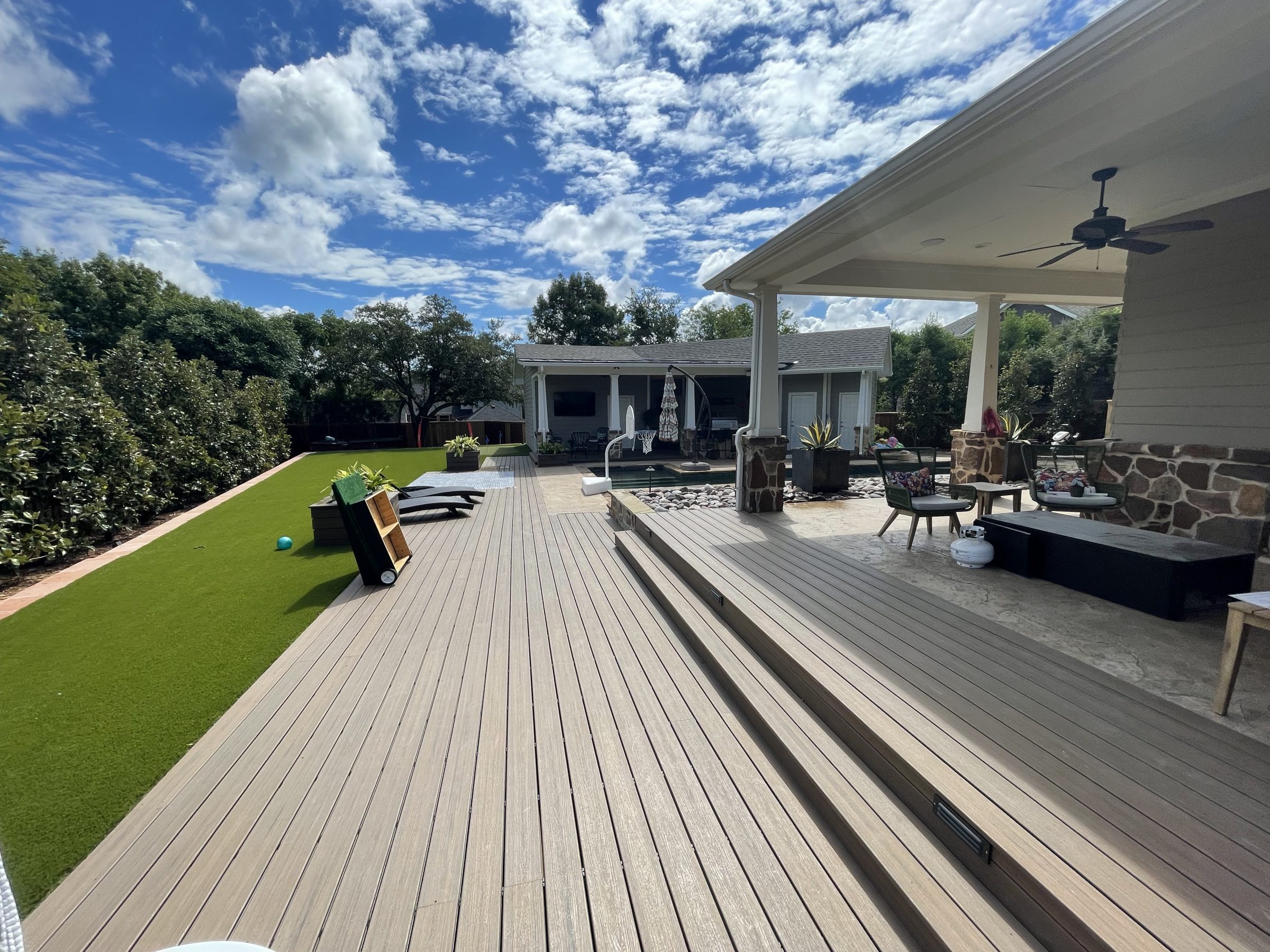 Sunny backyard patio with seating and greenery.
