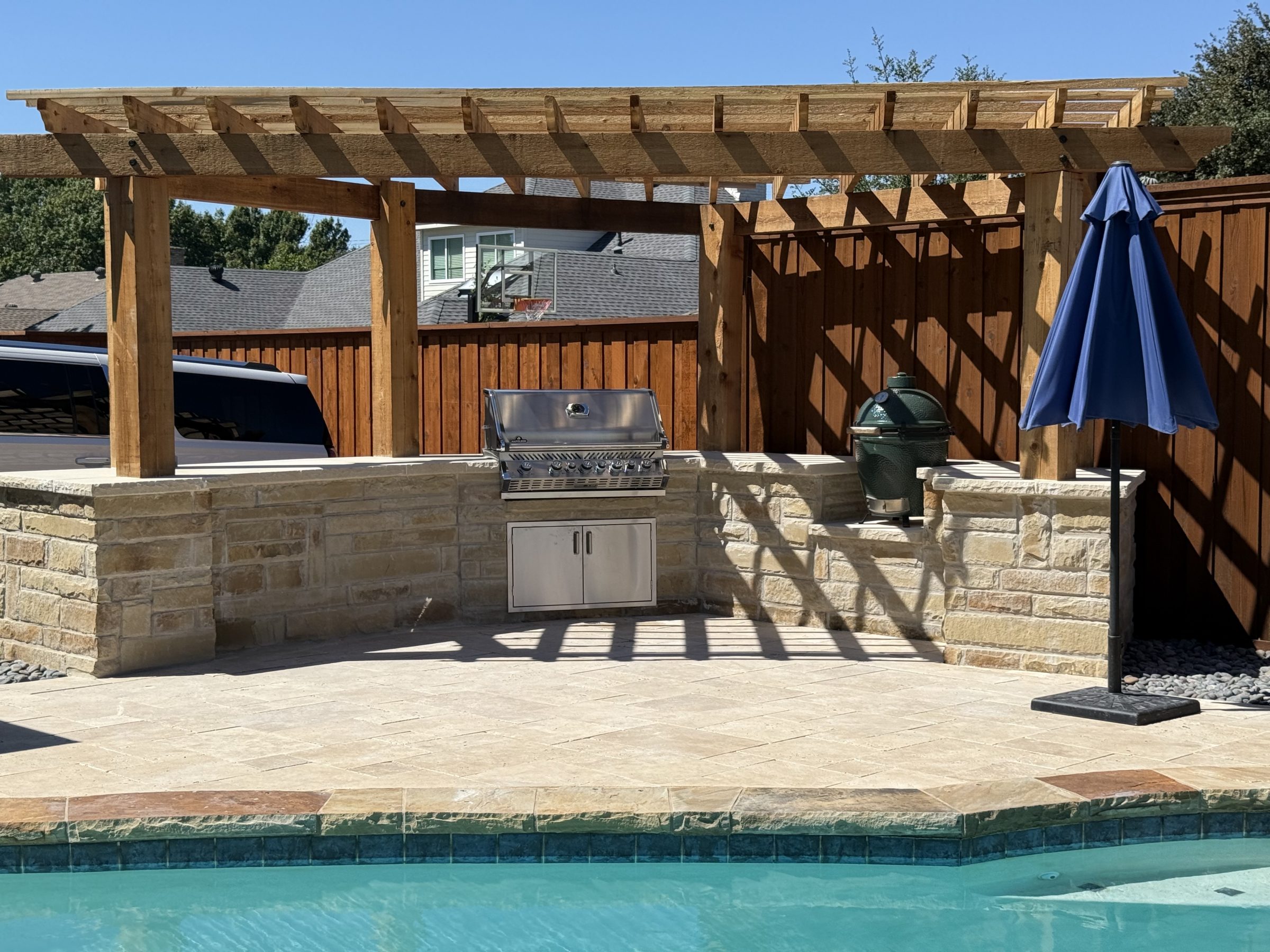 Outdoor grill and umbrella by the pool