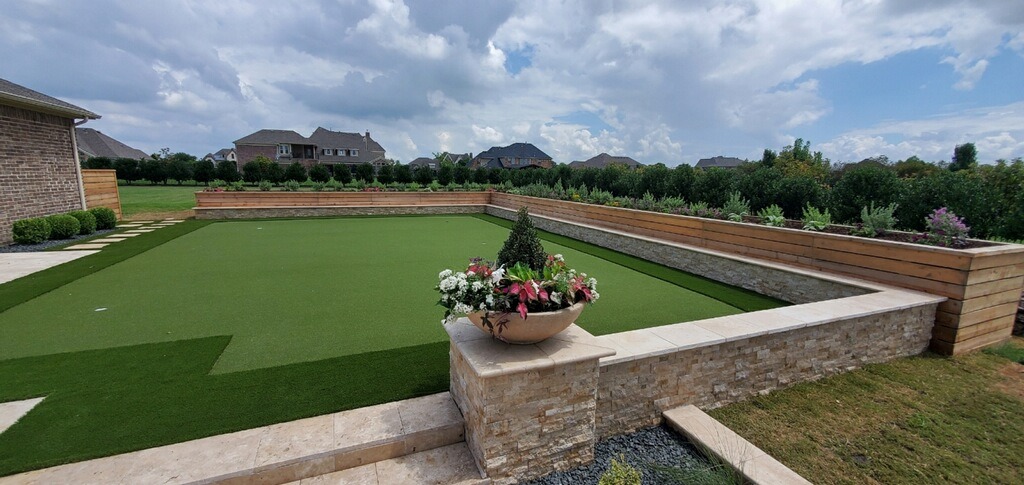 Manicured lawn with potted flowers and garden wall.