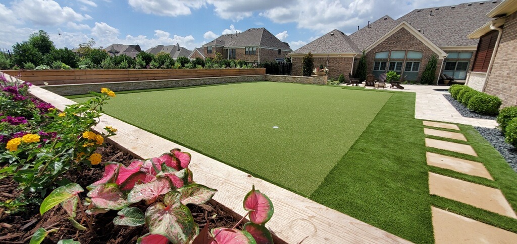 Residential backyard with artificial turf and flower garden.