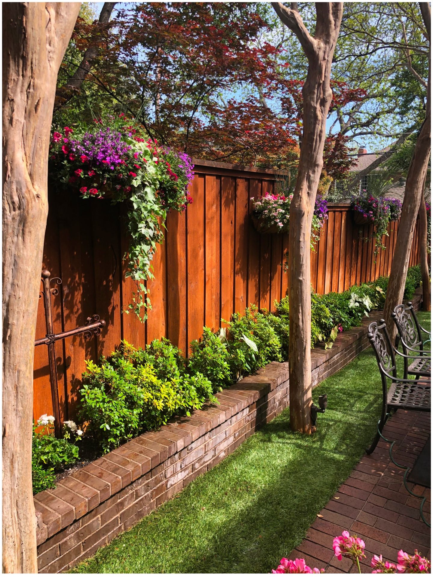 Garden with flowers, wooden fence, and patio chairs.