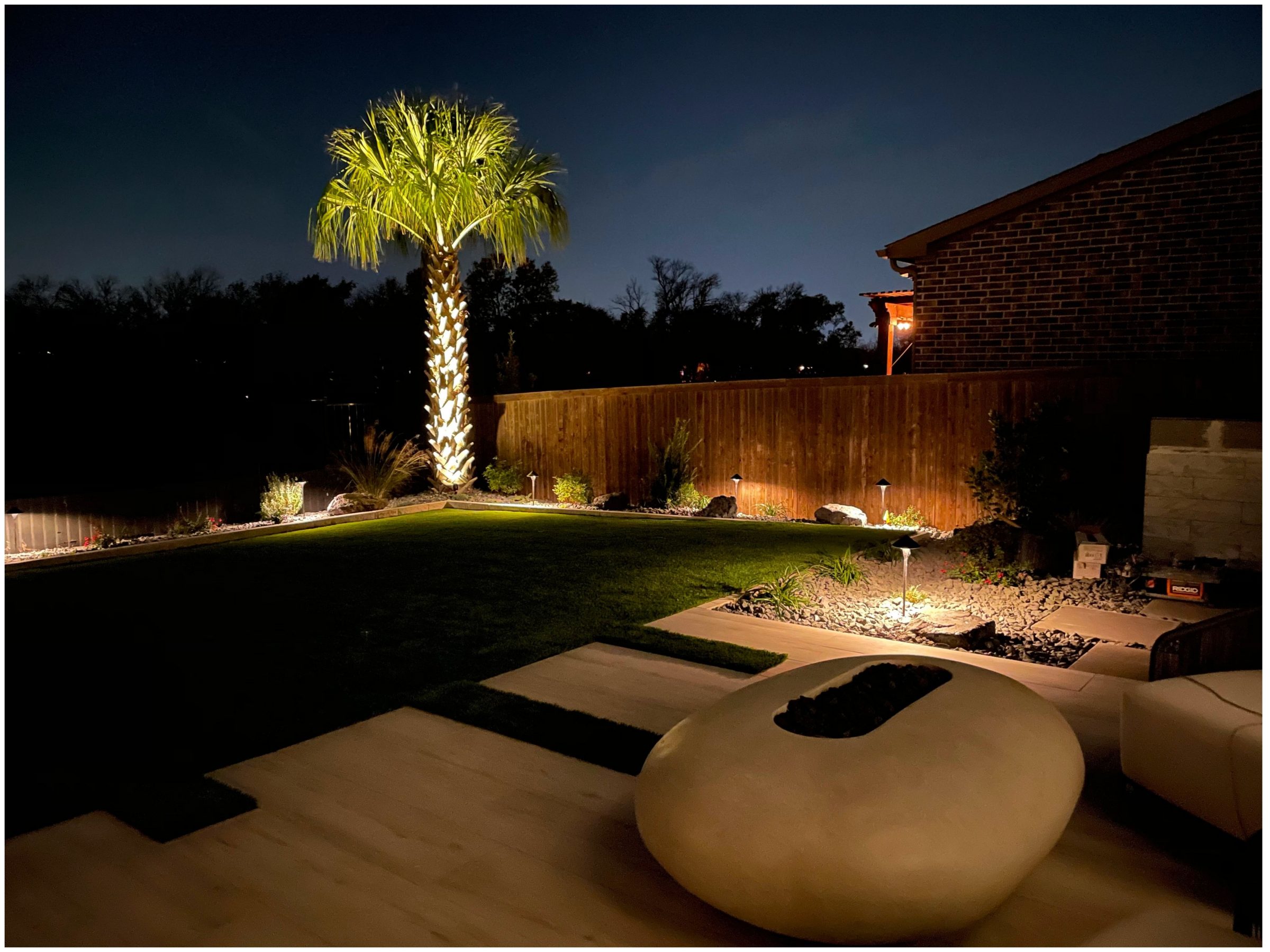 Backyard with illuminated palm tree at night.