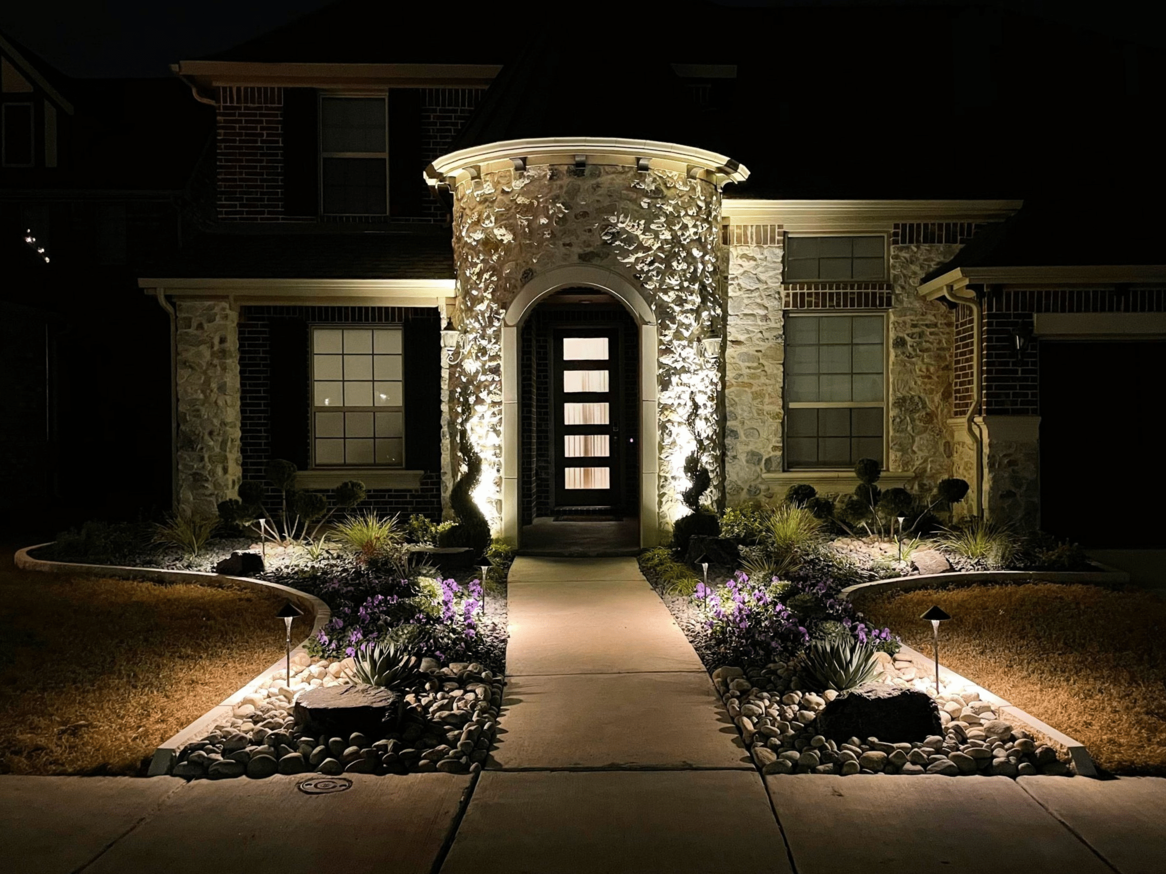 House with illuminated landscaping at night