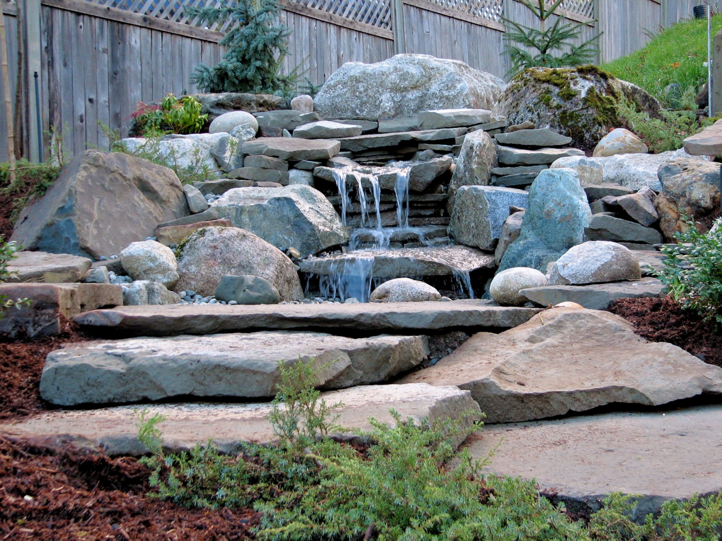 Garden waterfall with stones and greenery